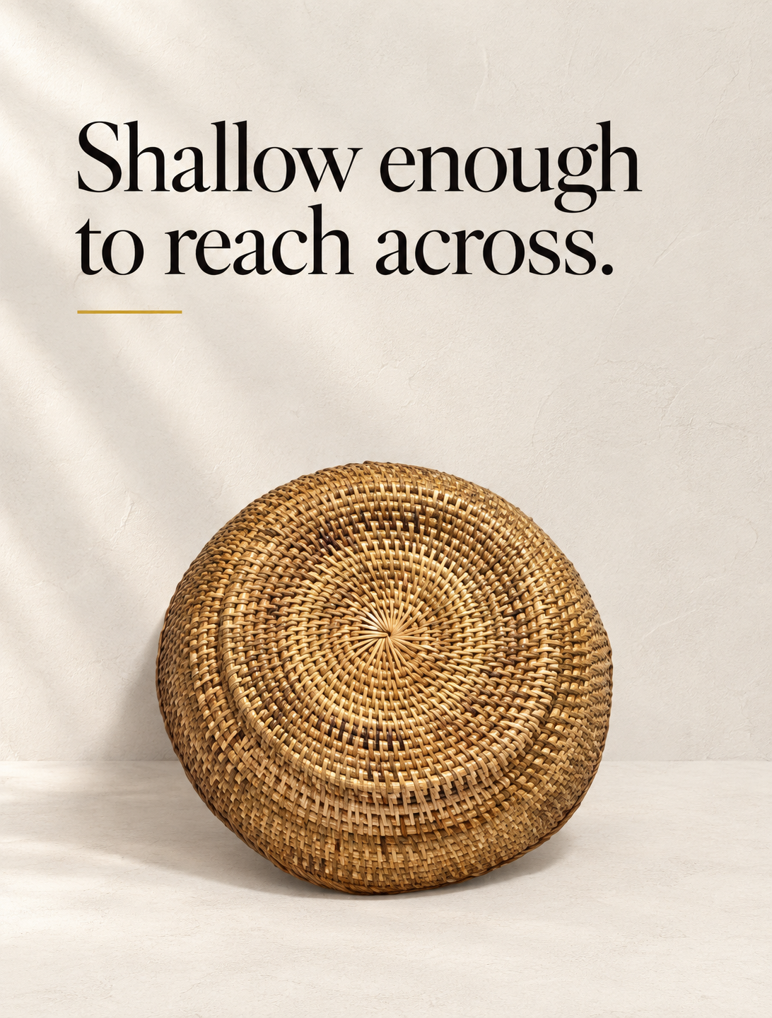 A shallow round bowl in undyed rattan, woven as one spiral from the centre out.